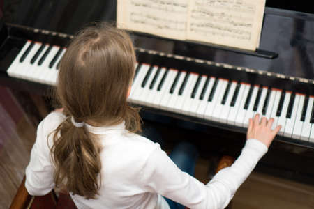 Little girl learning to play the piano.の写真素材