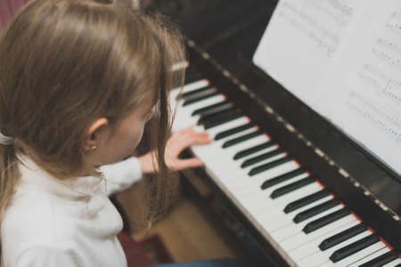 Little girl learning to play the piano.の写真素材
