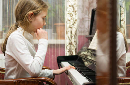 Little girl learning to play the piano.の写真素材