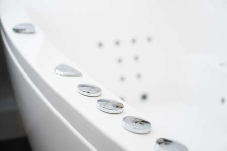 Hydromassage bathtub control buttons in bathroom.の写真素材