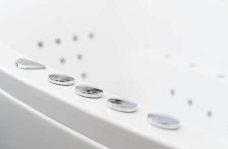 Hydromassage bathtub control buttons in bathroom.の写真素材