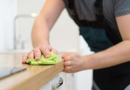 Cleaning service concept. Man cleaning kitchen furniture.の写真素材