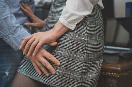 Sexual harassment at work. Boss touching his secretary in office.の写真素材