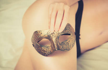 Sexual female body in black panties and arm holding carnival mask.の写真素材