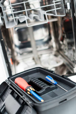 Toolbox in front of domestic dishwasher in the kitchen.の写真素材