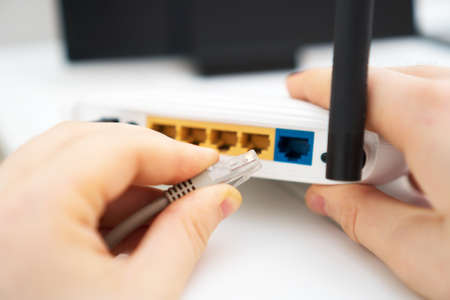 Man plugging internet cable into wifi router.の写真素材