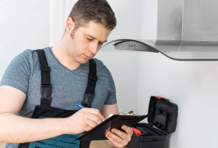 Handyman doing inspection of exhaust hood in the kitchen.の写真素材