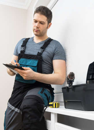 Professional contractor sitting at window with pen and notepad.の写真素材