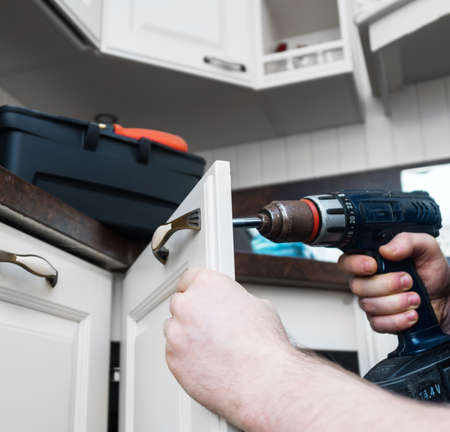 Professional handyman assembling kitchen door cabinet.の写真素材