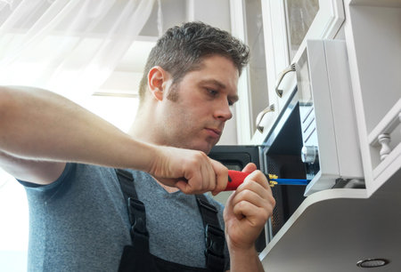 Male technician repairing microwave oven at home.の写真素材