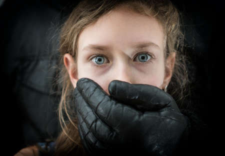 Man's hand covering mouth of scared young girl.の写真素材