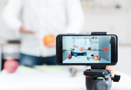 Man on the kitchen filming video. Vlogging concept.