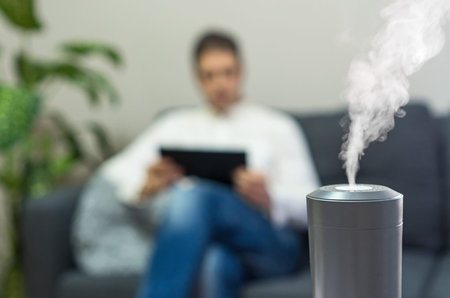 Air humidifier at living room. Man using tablet pc