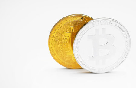 Physical version of silver and golden bitcoins on white background.