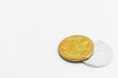 Physical version of silver and golden bitcoins on white background.