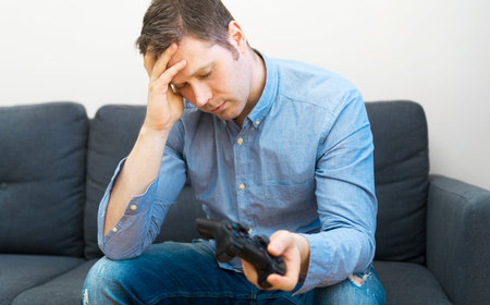 Sad man with gamepad in hands playing video game.