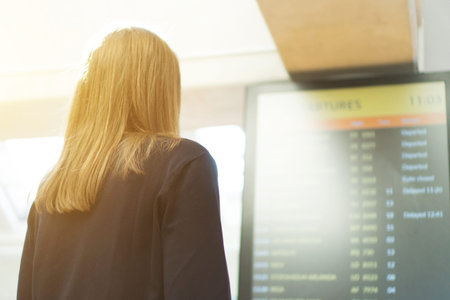 Woman in front of flight information board, checking her flight.