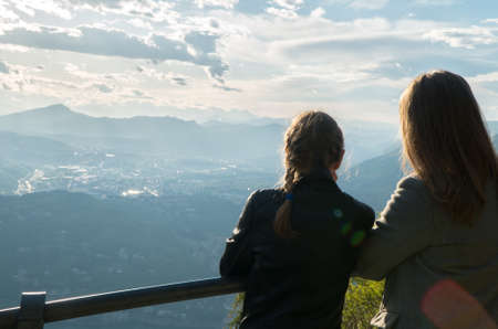 Woman and her daughter enjoying sunrise from top of mountain.の写真素材