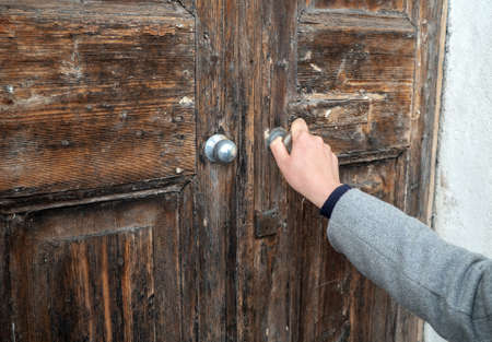 Woman opening very old wooden door.の写真素材