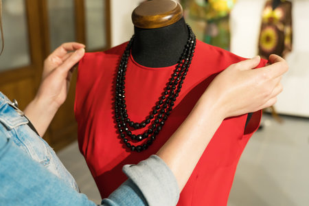 Female designer working with new model tailoring dress on mannequin in atelier.