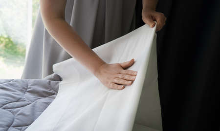 Room service. Woman making bed in hotel room.の写真素材