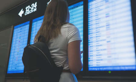 Woman in front of flight information board, checking her flight.の写真素材