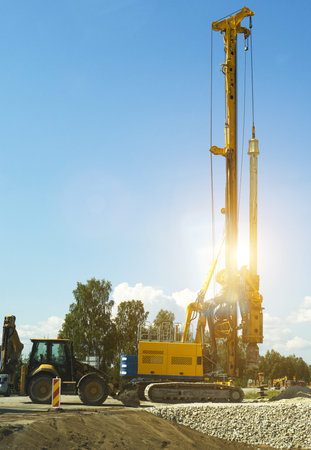 Hydraulic pile driver working on the road construction.