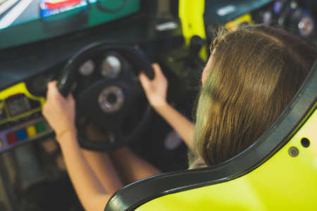Little girl playing racing simulator game in theme park.の写真素材