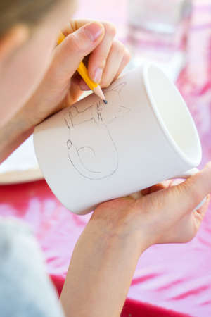 Child paints a mug in a pottery workshopの写真素材