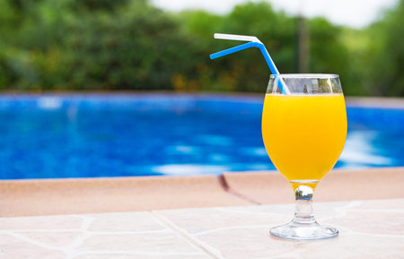 Orange juice near the pool. Space for text.