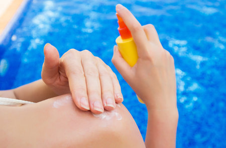 Woman applying sunblock cream on her shoulder.