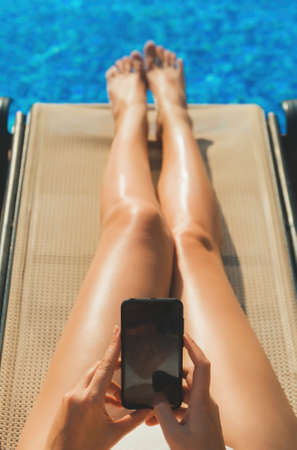 Woman using smartphone near the pool in the summer.の写真素材