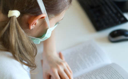 Little girl reading textbook during quarantine.の写真素材