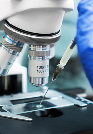 Virologist's hand in glove testing coronavirus vaccine under microscope.