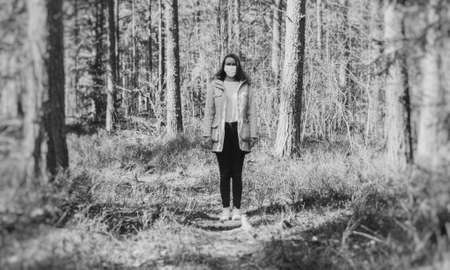 Woman in medical mask in the middle of the forest. Black and white.の写真素材