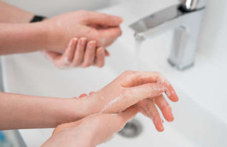 Family washing hands under water tap at home. Coronavirus protection concept.の写真素材