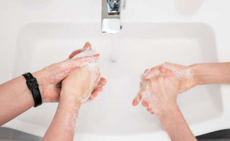Family washing hands under water tap at home. Coronavirus protection concept.の写真素材