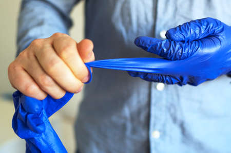 Man takes off his medical gloves. Covid-19 prevention.の写真素材