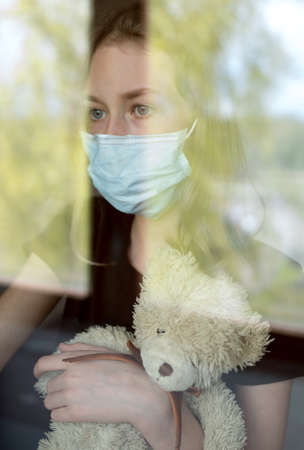 Little girl with toy behind the window during self isolation. Stay home.の写真素材