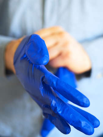 Man puts on his medical gloves. Covid-19 prevention.の写真素材
