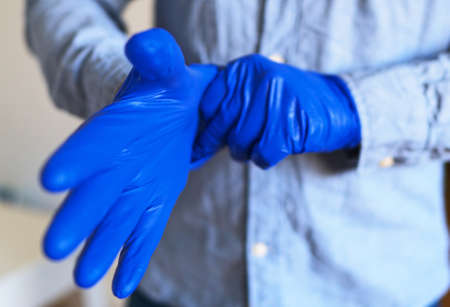 Man puts on his medical gloves. Covid-19 prevention.の写真素材
