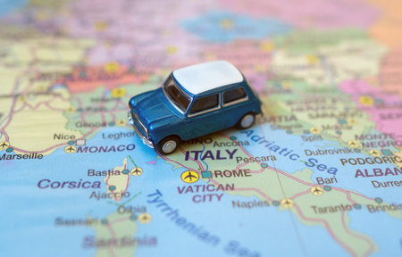 Small toy retro car on Europe map in Italy. Travel by car concept.の写真素材