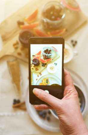 Woman doing photo of morning breakfast on mobile phone.の写真素材
