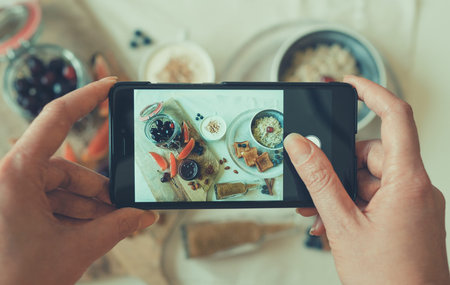 Woman doing photo of morning breakfast on mobile phone.の写真素材