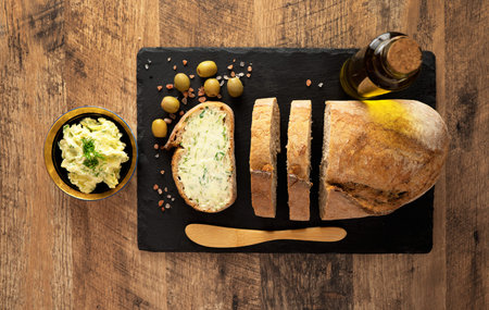 Sliced bread and rustic handmade herbs butter on the table.