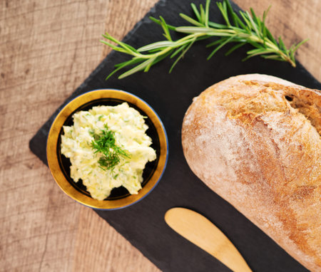 Freshly baked bread and rustic handmade herbs butter on the table.の写真素材