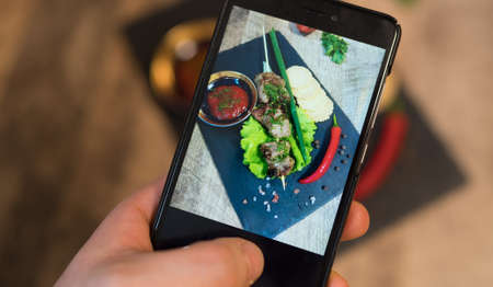 Woman doing photo of shashlik on mobile phone.の写真素材