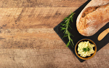 Freshly baked bread and rustic handmade herbs butter on the table.の写真素材