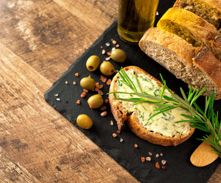 Sliced bread and rustic handmade herbs butter on the table.の写真素材