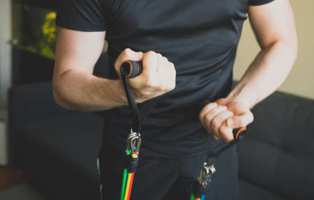 Man doing exercises with resistance bands at home.の写真素材